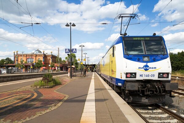 Blick auf den Triebwagen eines metronom-Zuges, links im Hintergrund der Hundertwasser-Bahnhof in Uelzen