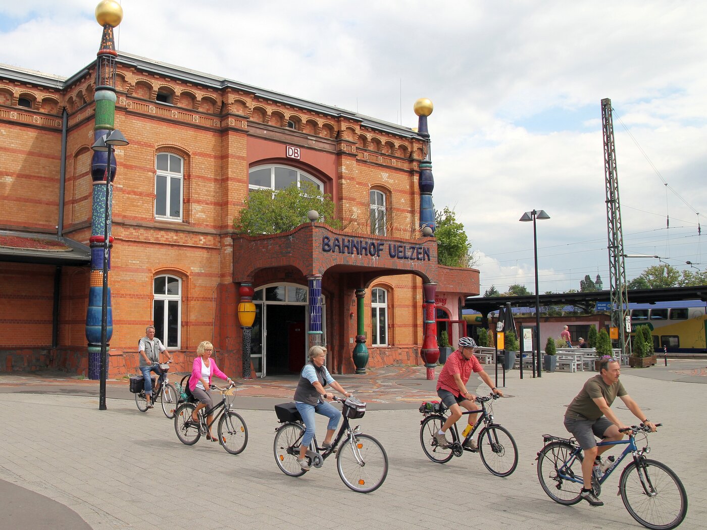 Eine Gruppe Radfahrer verlässt den Vorplatz des Hundertwasser-Bahnhofs in Uelzen.