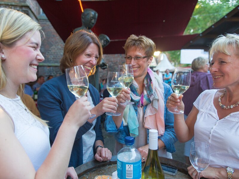 Vier Frauen prosten sich auf dem Weinmarkt in Uelzen mit Weißwein zu