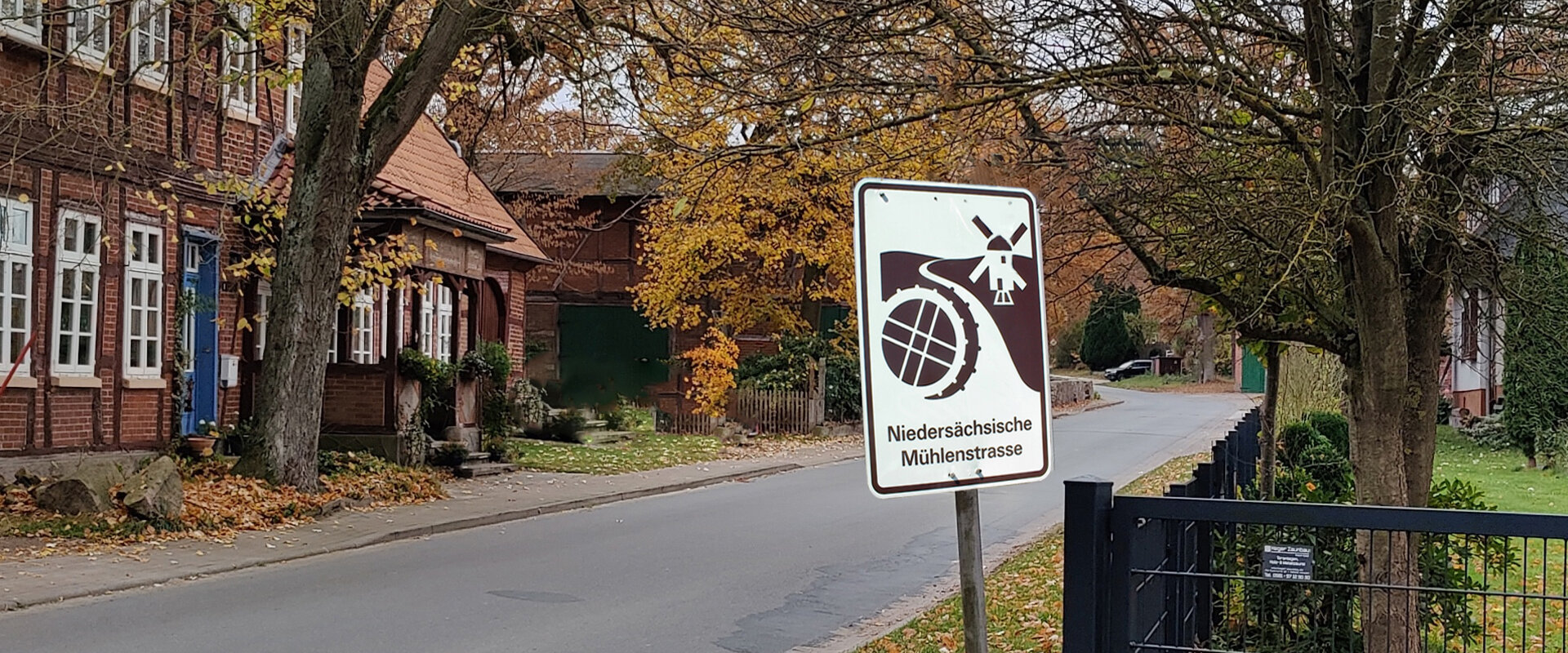 Herbstliche Dorfstraße mit einem Schild der Niedersächsischen Mühlenstraße